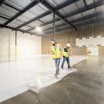 Professional applying epoxy resin flooring with roller on concrete garage floor during DIY installation process