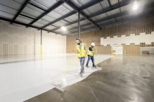 Professional applying epoxy resin flooring with roller on concrete garage floor during DIY installation process