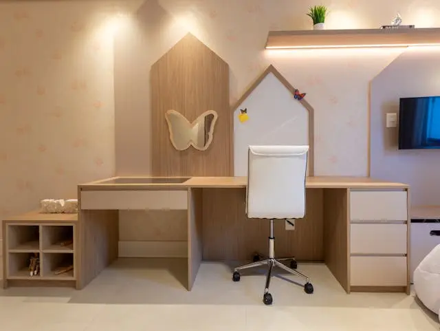 Modern small teenage bedroom setup with a minimalist wooden study desk, white chair, wall-mounted shelves, and soft lighting designed for a compact stylish room.